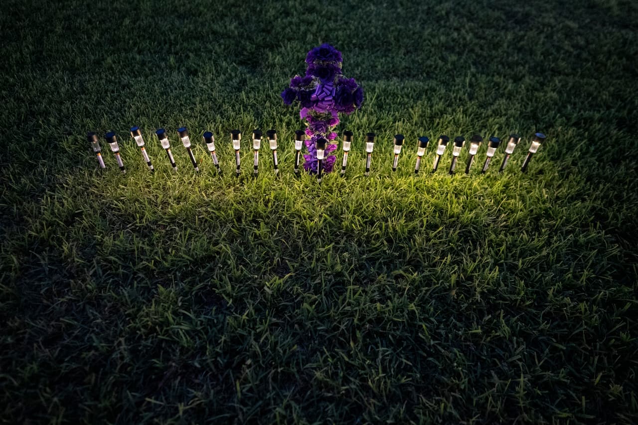 Luces iluminan una cruz hecha de flores en la plaza del pueblo. Muchos niños sobrevivientes del tiroteo conocían o habían sido alumnos de las maestras asesinadas.