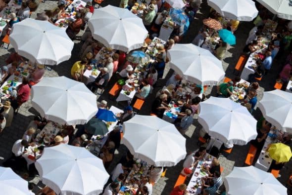 Las personas comparten sus alimentos bajo los paraguas en el Festival de la Paz de Augsburgo, al sur de Alemania.