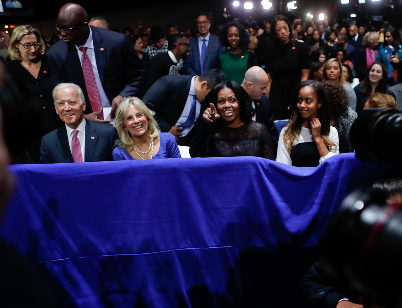 Joe Biden, su esposa Jill, Michelle Obama y Malia Obama toman asiento frente al escenario.