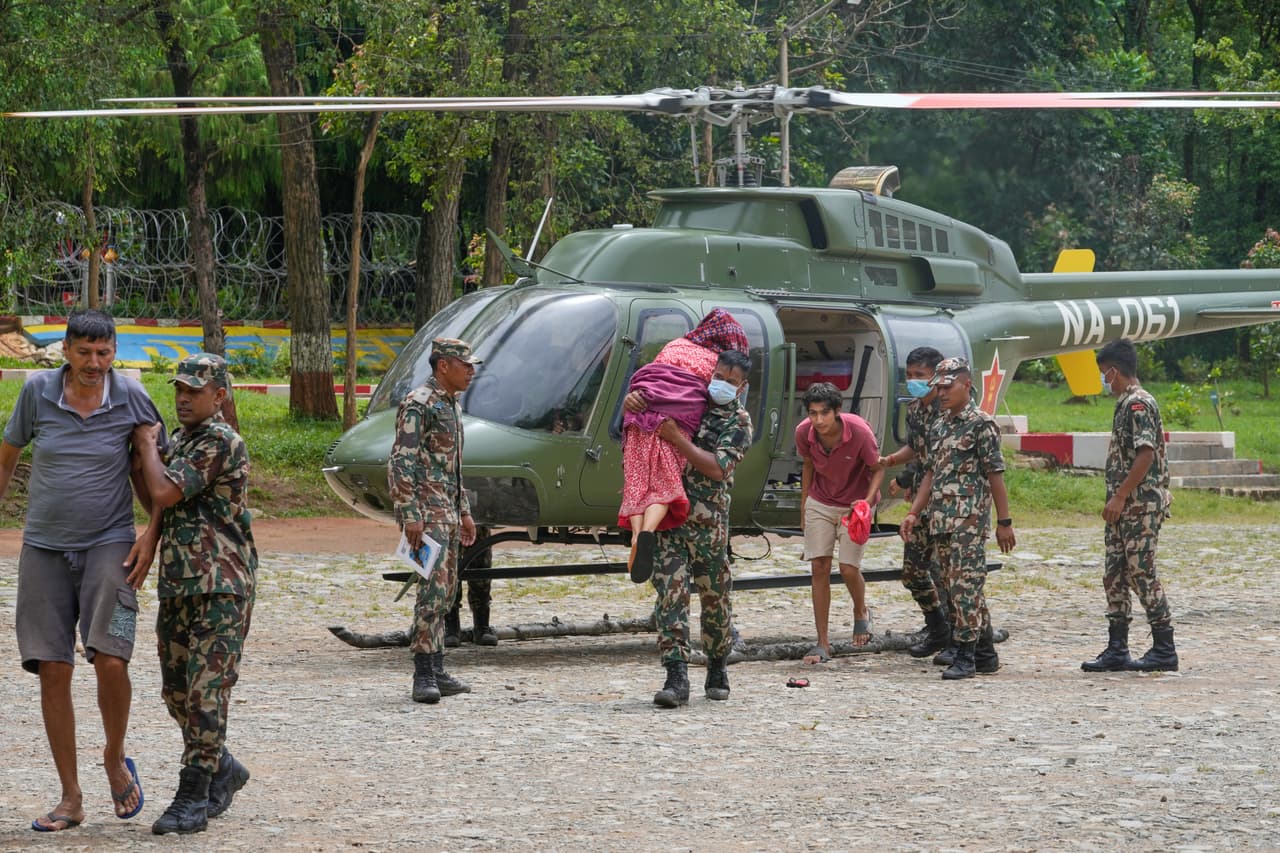 Soldados del ejército nepalí ayudan a personas rescatadas de zonas aisladas por inundaciones repentinas a desembarcar de un helicóptero en el distrito de Nuwakot, Nepal, el sábado 29 de agosto de 2026.