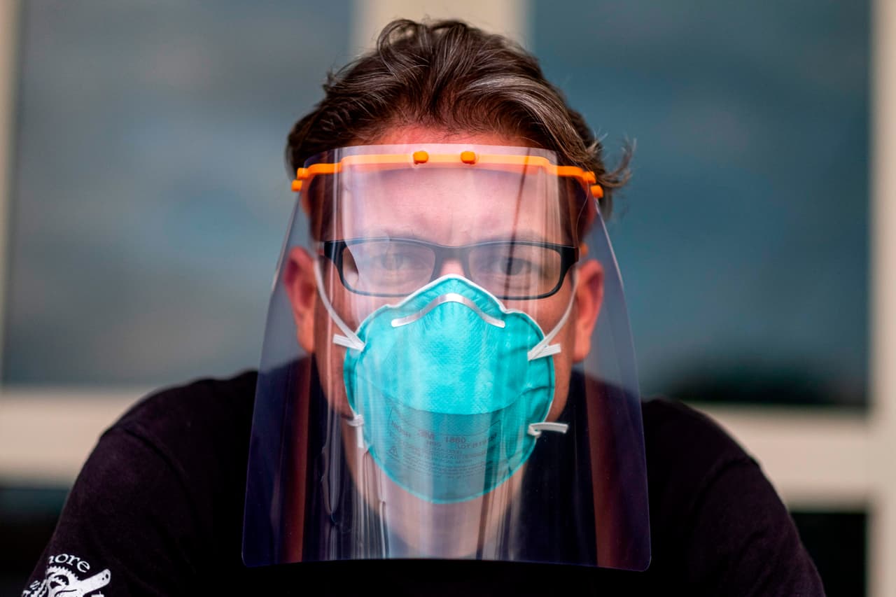 El Dr. Jonathan Alistair posa para una foto con uno de sus protectores faciales en su casa.