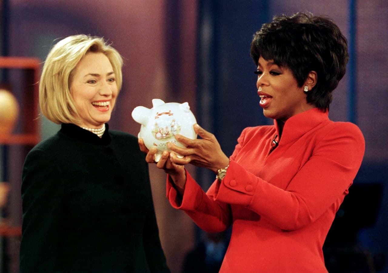 <b>La colaboración de la primera dama. </b>La ex primera dama, exsenadora, ex secretaria de Estado y ex candidata presidencial por el Partido Demócrata Hillary Clinton visitó el programa de Oprah varias veces. En la fotografía de 1997, Winfrey sostiene una alcancía llena de monedas que le llevó entonces la esposa del presidente para su organización de caridad llamada Oprah's Angel Network, encargada de ayudar a pagar los estudios universitarios de jóvenes de bajos recursos en EEUU.