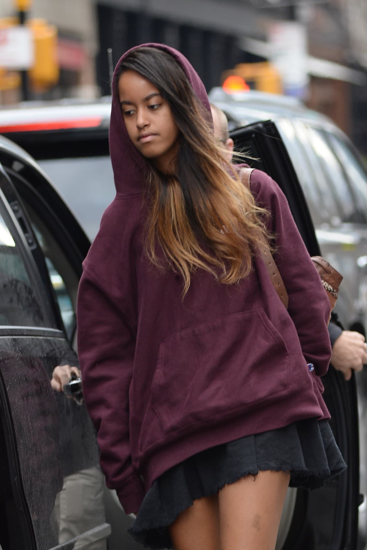 Malia Obama usa un hoodie marrón, minifalda sin medias veladas y sneakers.