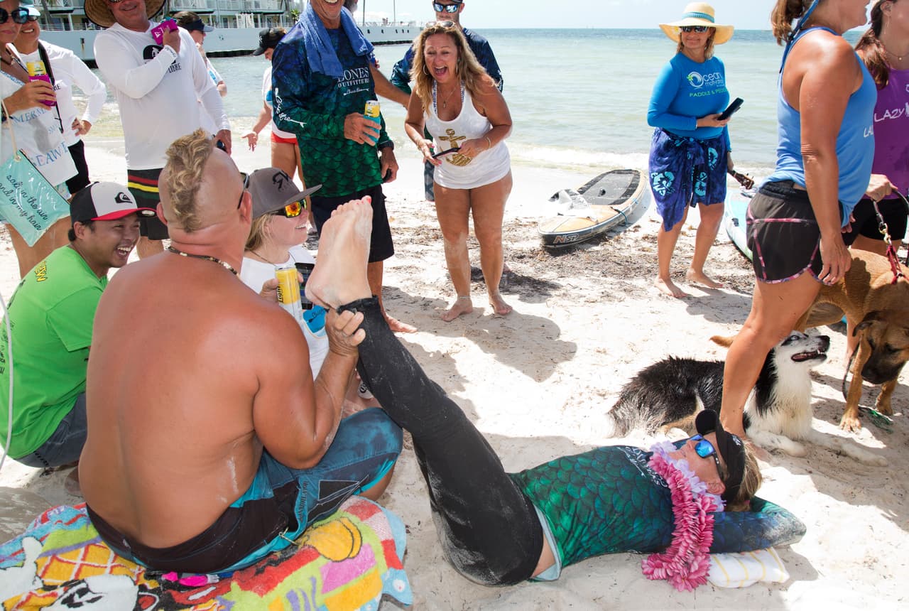 Jeff Keine sostiene las piernas de Victoria Burgess, después de que Burgess completara un viaje stand up paddleboard de La Habana, Cuba a Key West, Florida, el miércoles 27 de junio de 2018.