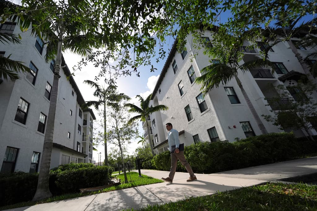 Alvaro Duran Stella, de 47 años, un venezolano con estatus de protección temporal (TPS), que estudio para convertirse en asistente legal y que ahora trabaja en Doral, Florida, camina de vuelta a su apartamento tras trabajar a distancia en el club de su urbanización, el sábado 5 de abril de 2025 en Miramar, Florida, EE.UU. (AP Foto/Rebecca Blackwell)