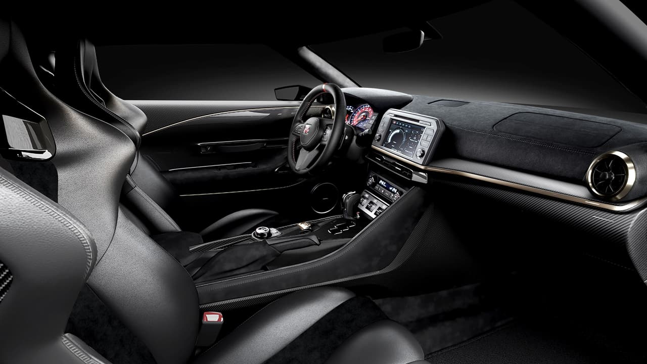 En la cabina las cosas también cambian sustancialmente. El diseño del interior fue hecho conjuntamente por los 
<b>estudios de diseño de Nissan en San Diego y Londres</b>. No nos imaginamos como resolvieron las diferencia horaria de 9 horas pero el resultado habla bien de la colaboración. El uso de dos texturas de fibra de carbono en la consola central, panel de instrumentos y puertas junto con cuero italiano negro y uso liberal de Alcantara logran una cabina muy elegante. El volante de fibra de carbono cubierto en Alcantara fue diseñado especialmente para este modelo.