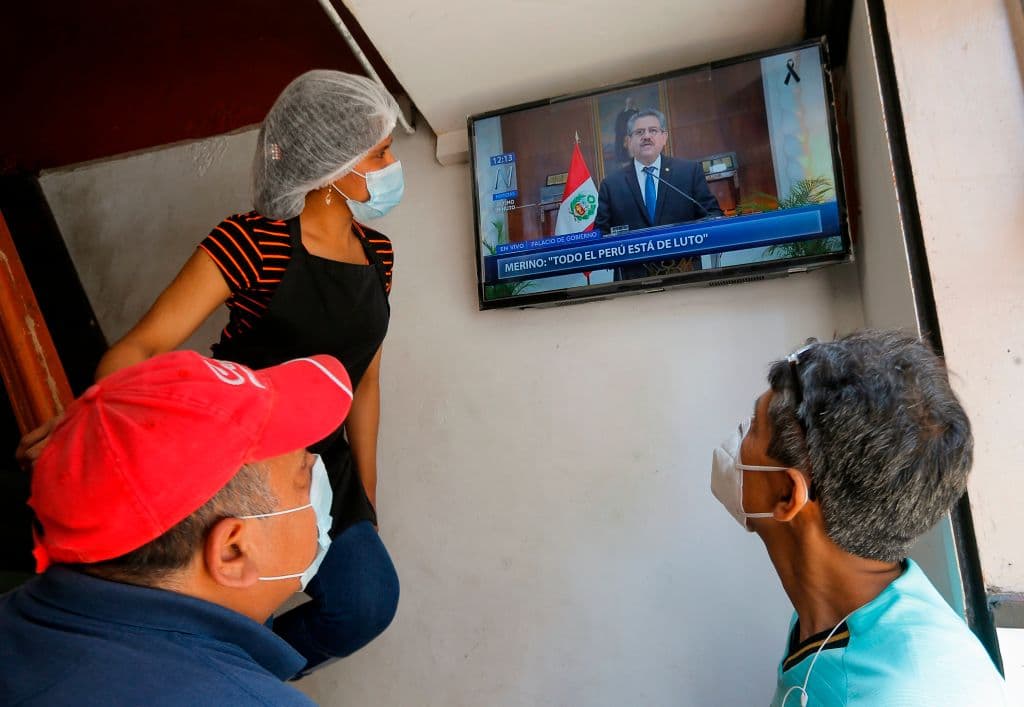 En un bar, varias personas con mascarillas veían el mensaje televisado de Manuel Merino este domingo, en el que anunció "su dimisión irrevocable". Perú es uno de los países más castigados del mundo por la pandemia del coronavirus.