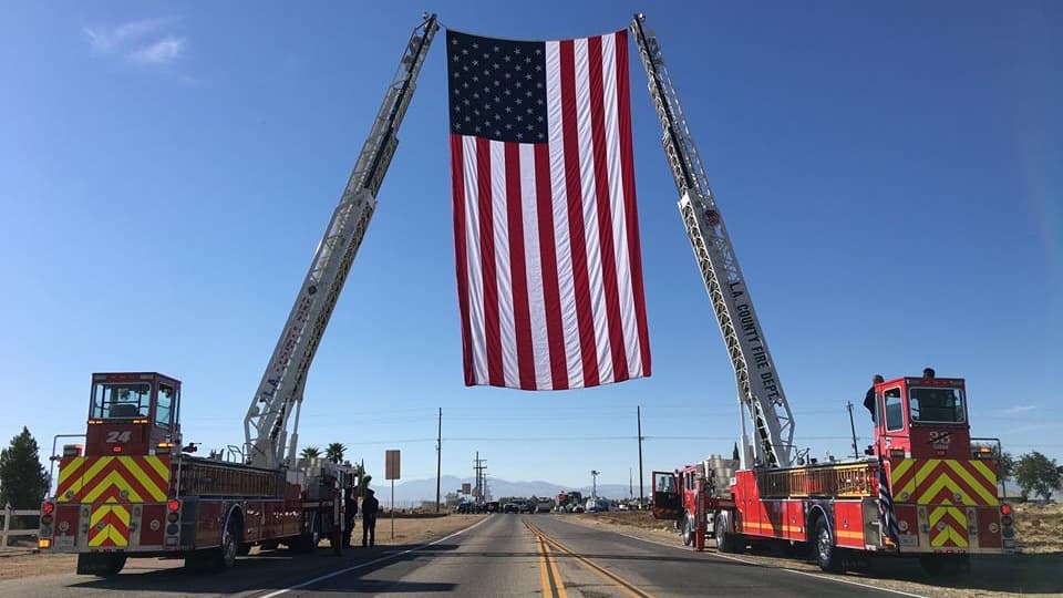 Los bomberos recibieron la caravana funeraria con el despligue de una bandera gigante de Estados Unidos.