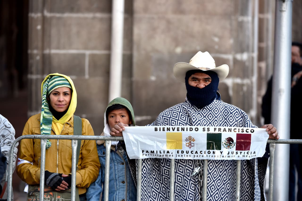Este hombre de sombrero y cara tapada muesra un cartel con la bandera de México y la del Vaticano.