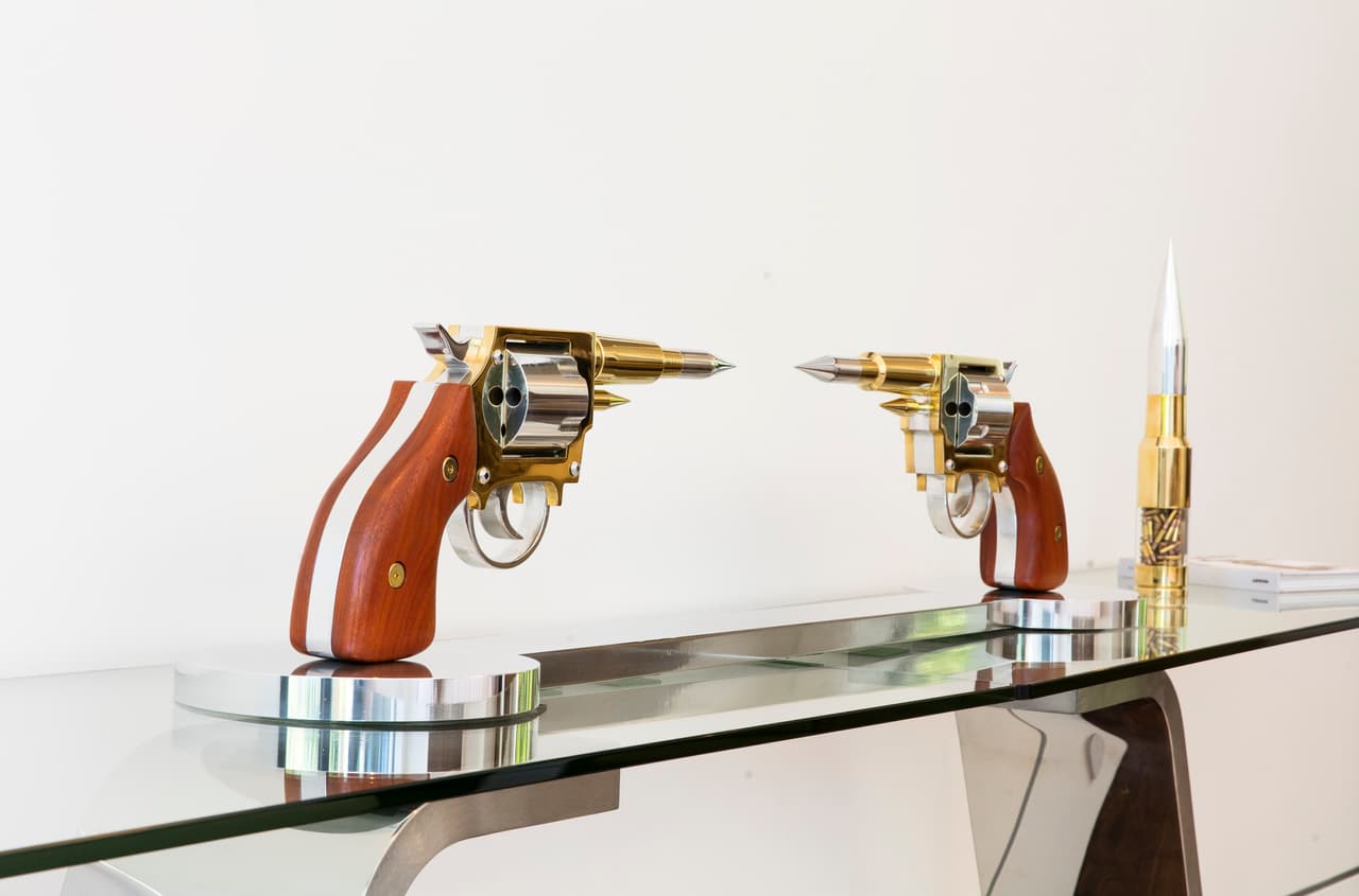 Escultura de dos pistolas y una bala con revestimiento de cromo elaborada por Gale Hart, quien ha convertido en piezas de arte estos instrumentos.