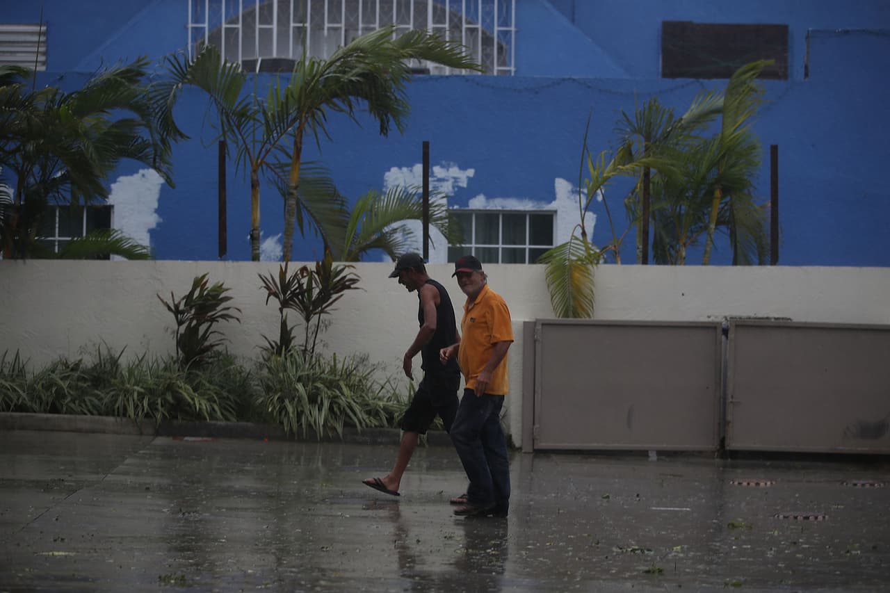 Dos hombres caminando por la calle en medio de los fuertes vientos y la lluvia provocados por huracán en Miami este domingo. El huracá categoría 4 comenzó a azotar EEUU con vientos mayores a 130 mph.