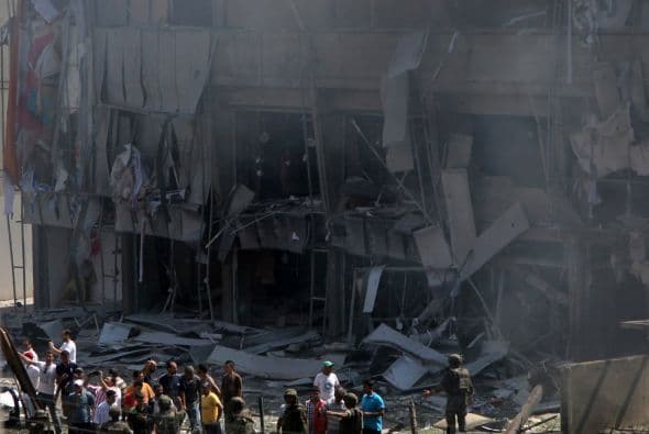 Lebanese citizens stand in front of a severely damaged building as they gather outside al-Salam mosque, near the house of former Lebanese police chief Ashraf Rifi,