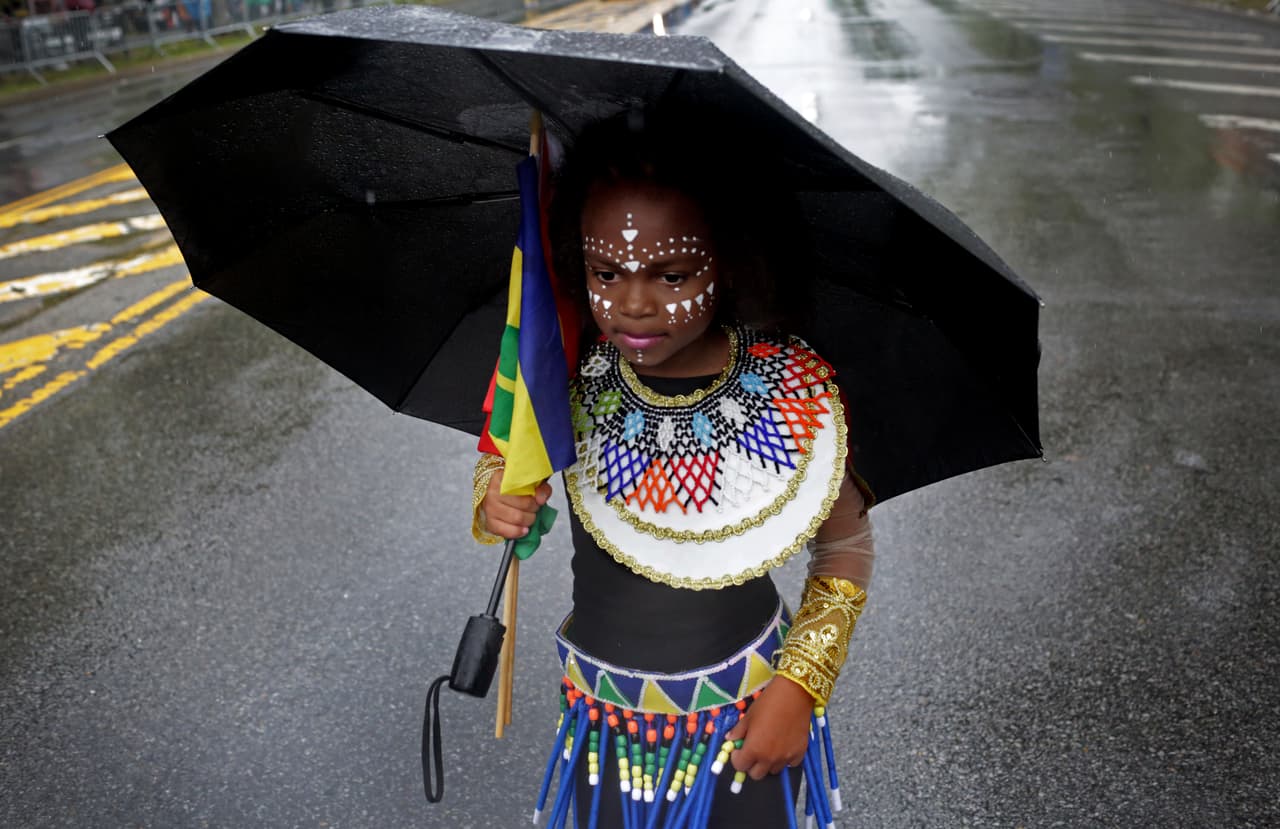 Una niña en disfraz se protege de la lluvia durante el desfile.