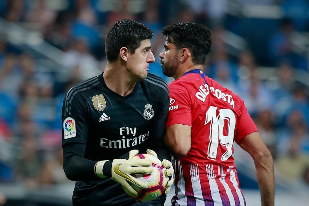 El arquero belga Thibaut Courtois (izquierda) contiene el balón ante el delantero del Atlético de Madrid, Diego Costa (derecha).