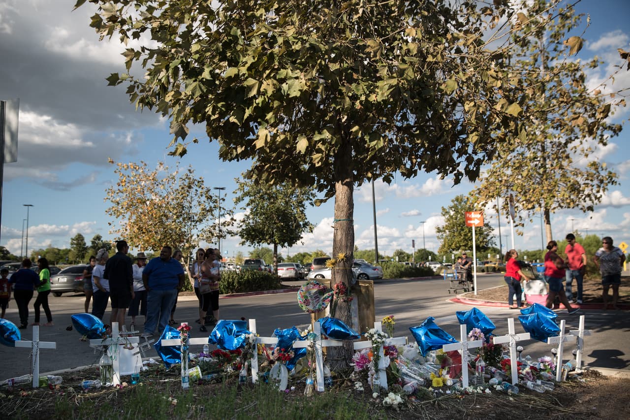 Diez cruces fueron clavadas alrededor del árbol de la tienda Walmart, una por cada inmigrante fallecido. En ellas han guindado rosarios, recostado flores y cada una lleva atado un globo azul que poco a poco se han ido desinflando por el calor inclemente.