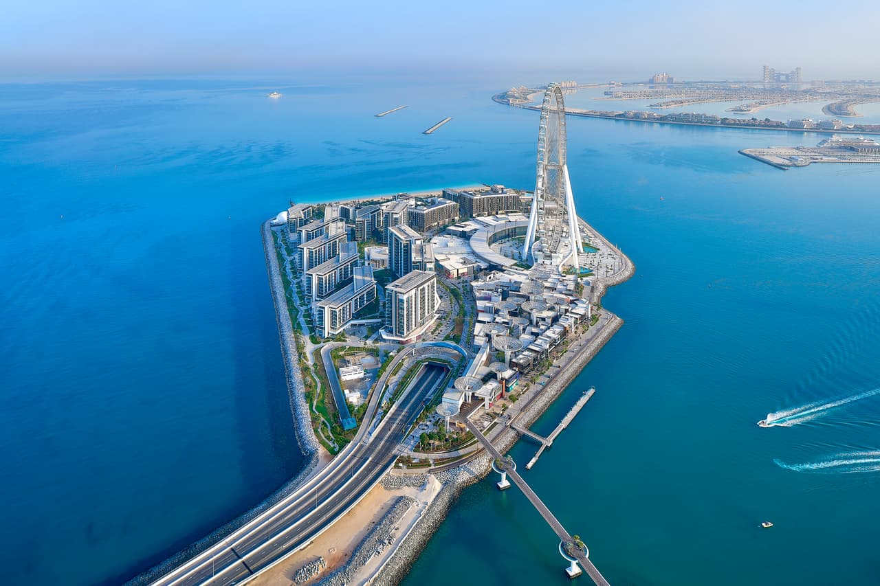 Una vista de la isla artificial Bluewaters, donde se instaló la inmensa rueda. Alcanza los 820 pies de altura (unos 250 metros) y ofrece vistas impresionantes de 360 grados de Dubai. Es 82 metros más alta que la noria más alta del mundo en funcionamiento, el High Roller de Las Vegas (550 pies, unos 170 metros).
<br>
<br>Ain Dubai tiene casi el doble del tamaño de la rueda London Eye en Reino Unido, que se eleva sobre el río Támesis a unos 135 metros (442 pies).
