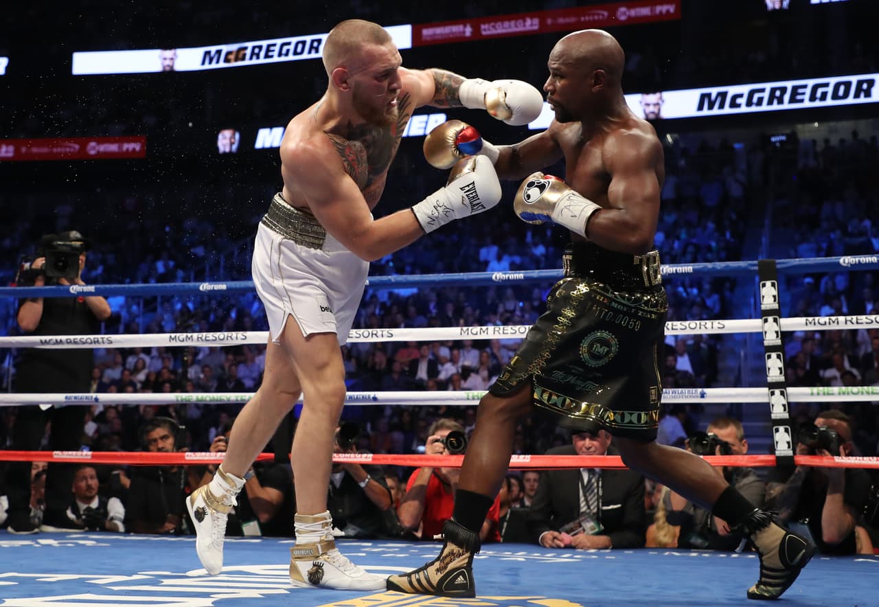 LAS VEGAS, NV - AUGUST 26: (L-R) Conor McGregor throws a punch at Floyd Mayweather Jr. during their super welterweight boxing match on August 26, 2017 at T-Mobile Arena in Las Vegas, Nevada. (Photo by Christian Petersen/Getty Images)