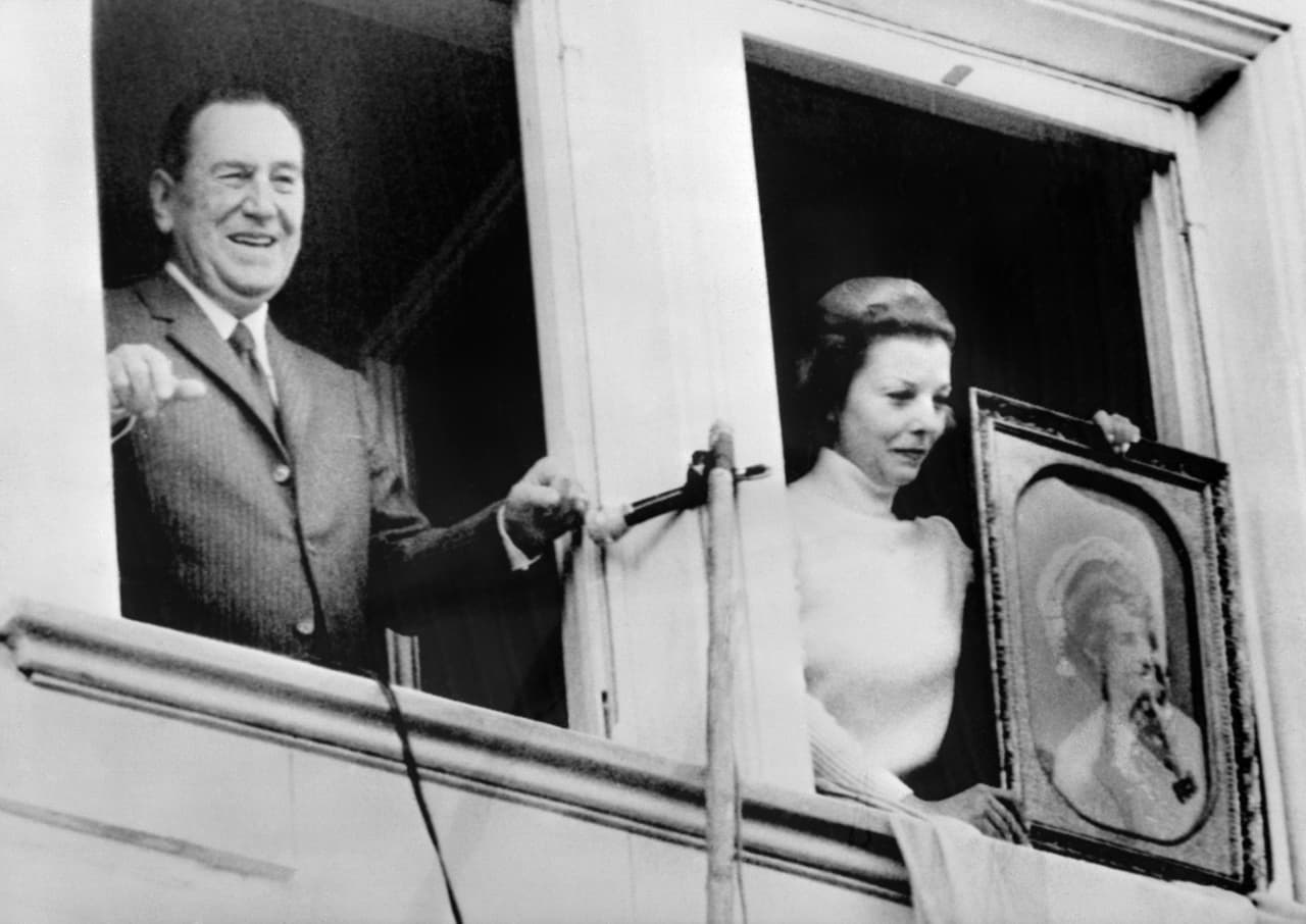 En la foto, Perón con su última esposa, Isabel Perón, en su retorno a Argentina tras la larga proscripción. Isabel Perón sostiene un cuadro con el rostro de Evita. 
<br>
<br>En 1974, Perón muere siendo presidente y asume su compañera y vicepresidenta, 'Isabelita', 
<b>quien hace los arreglos para que el cuerpo de Evita vuelva a Argentina. </b>
