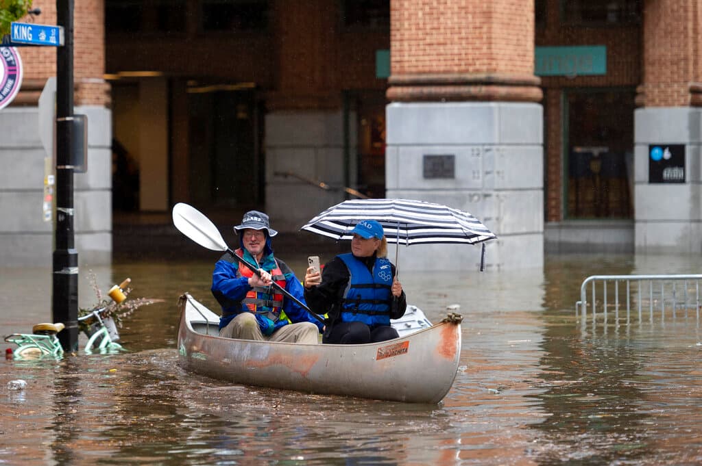 Los residentes del casco antiguo, Heidi DeuPree, a la derecha, y Keith Harmon navegan en canoa por una calle inundada por el río Potomac, el viernes 29 de octubre de 2021.