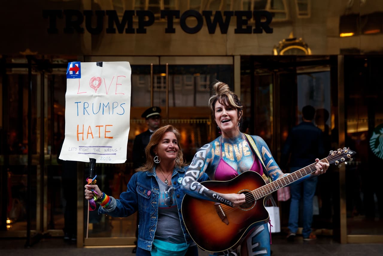 Guitarra en mano Gigi Love expresaba sus inquietudes frente a la Torre Trump, donde otra manifestante se le sumó con una pancarta que proclama que el amor triunfa ante el odio.
