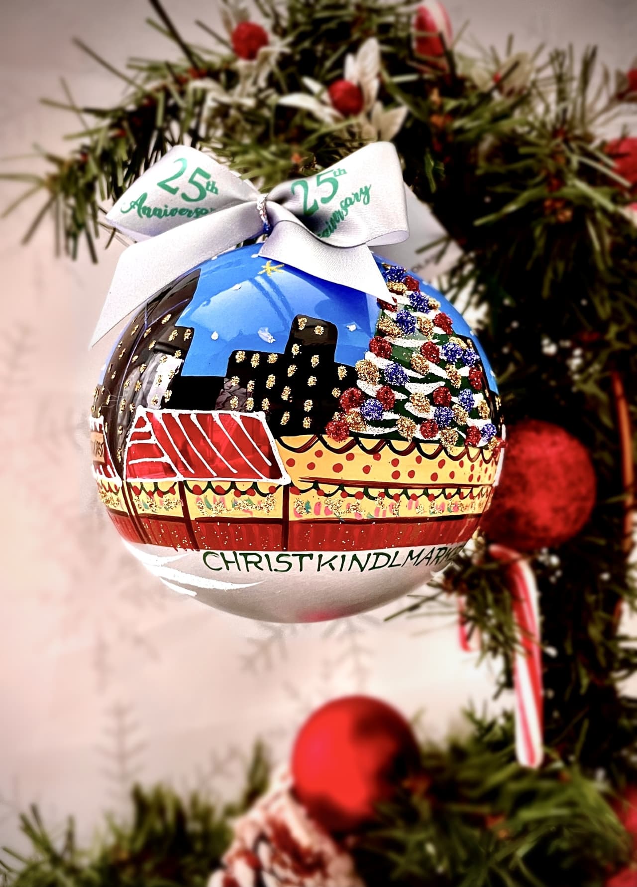 Este año marca el lanzamiento del primer adorno anual Christkindlmarket. El nuevo recuerdo de alta calidad es una esfera de vidrio soplado especial pintado a mano de Europa, completo con una escena de pintorescas rayas rojas y blancas, con fuegos artificiales de celebración.