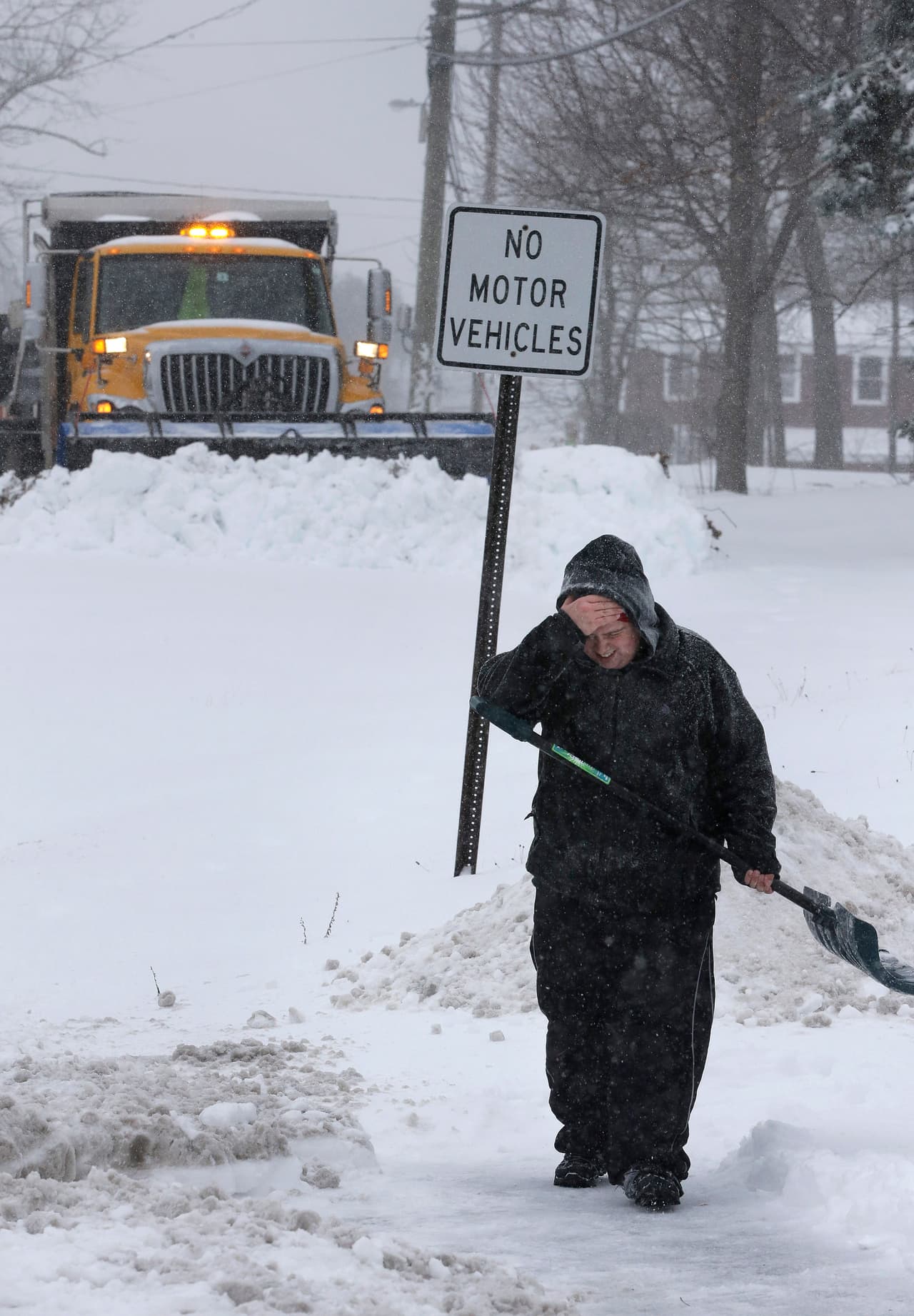 Corey Najman, de Portsmouth, New Hampshire, sostiene su mano a la cara, mientras retira la nieve de su casa con una pala