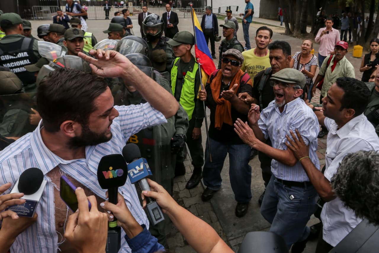 Manifestantes del chavismo, algunos identificados por testigos como miembros de 'colectivos', agreden al diputado opositor Juan Requesens, frente a la Policía Nacional Boliviariana el 31 de marzo de 2017.