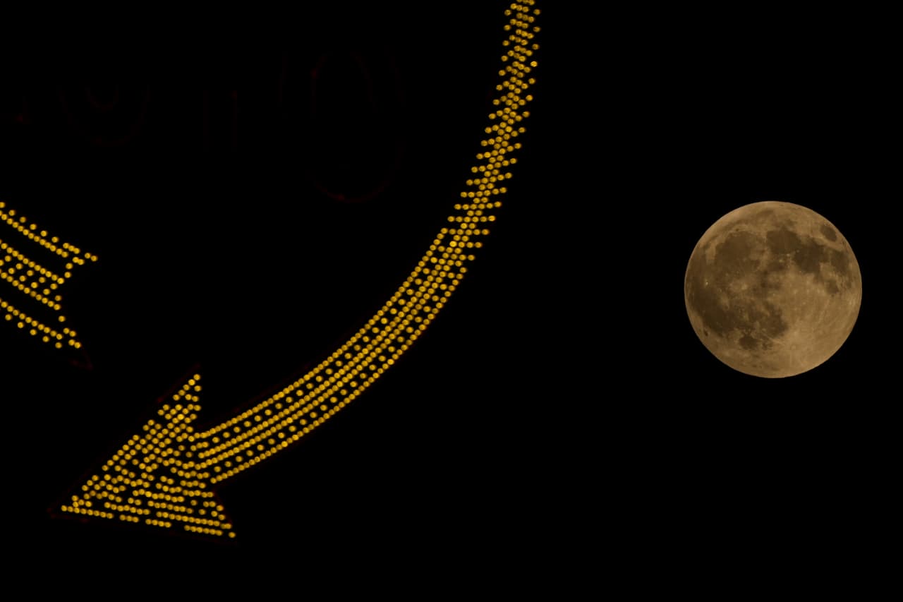 La luna llena se eleva tras un letrero en el centro de Kansas City, Misuri, antes de un eclipse lunar el jueves 27 de agosto de 2026.