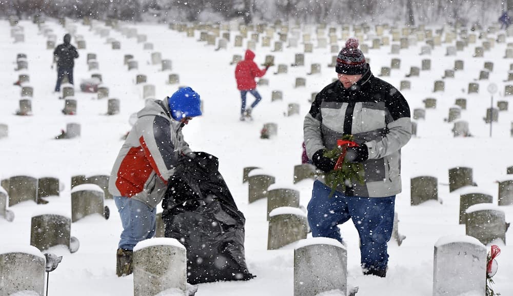 Dos personas colacan coronas en un cementerio de soldados en Erie.