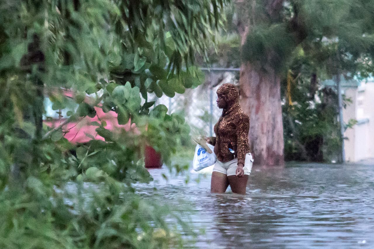 Una mujer camina por una calle de Nassau, Bahamas, donde el nivel del agua sobrepasa la altura de sus rodillas. El meteoro se quedó sin moverse durante horas en el noroeste del archipiélago, provocando inundaciones en las islas de Ábaco y Gran Bahama, con paredes de agua que alcanzaron el segundo piso de los edificios, atrapando a la gente en los áticos y anegando el aeropuerto de Gran Bahama en seis pies (1.8 metros) de agua.