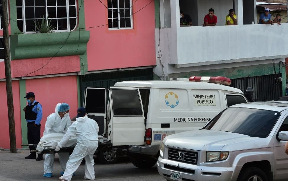 Forensic personnel wear protective suits as they carry the corpse of a victim at the poor La Rosa neighborhood, in the southern outskirts of Tegucigalpa on June 14, 2020, amid the new coronavirus pandemic.
