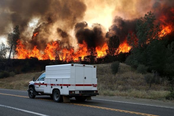 Las llamas arden detrás de un vehículo.
