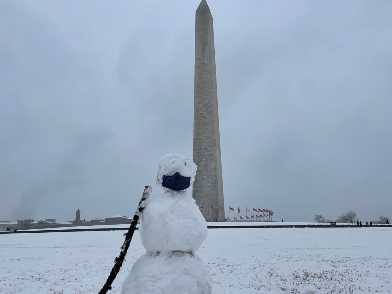 Un muñeco de nieve con un tapabocas por el coronavirus se ve cerca del Obelisco ubicado en el National Mall en Washington DC. Muchos turistas y residentes han llegado hasta el sector para apreciar la nevada.