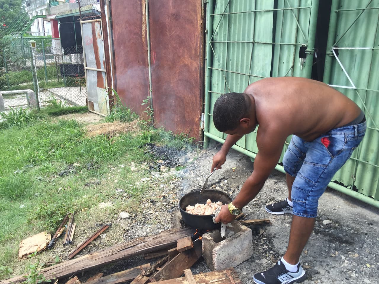A man cooks fresh butched pork ('chicharon') by the side of the road in Vieja Linda, a barrio of pot-holed streets in southern Havana