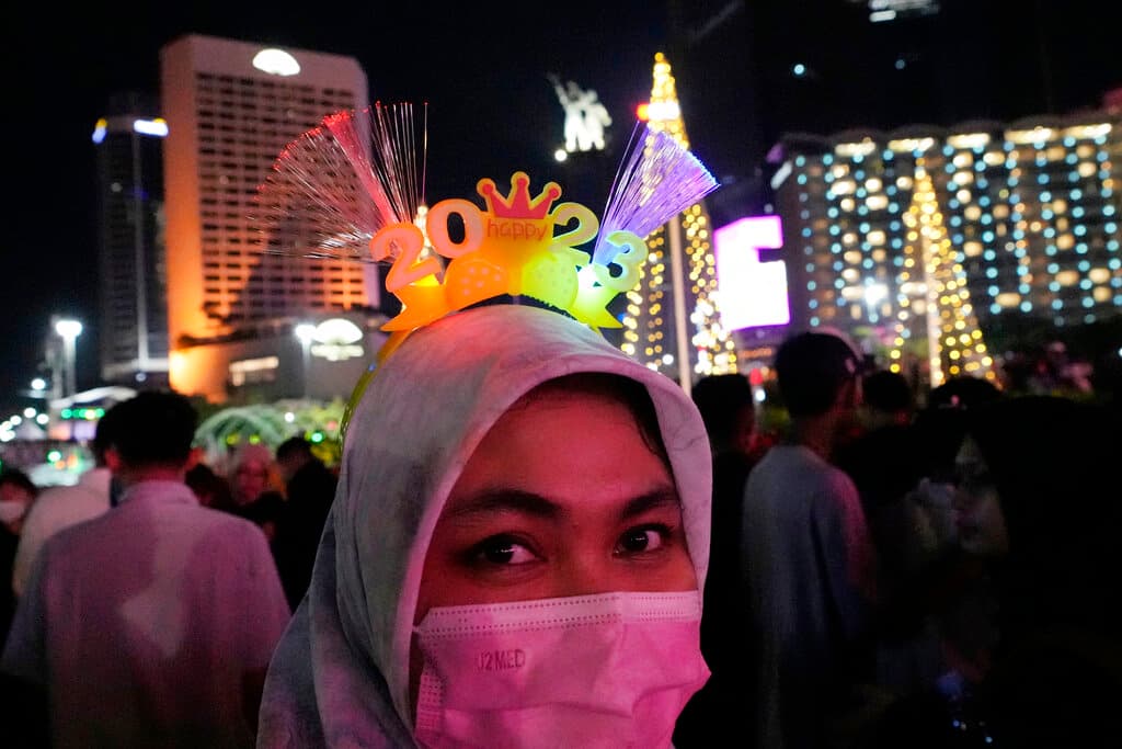 Una mujer con mascarilla hace un selfie en el distrito de negocios de Jakarta, en donde muchos se reúnen para esperar el año nuevo.