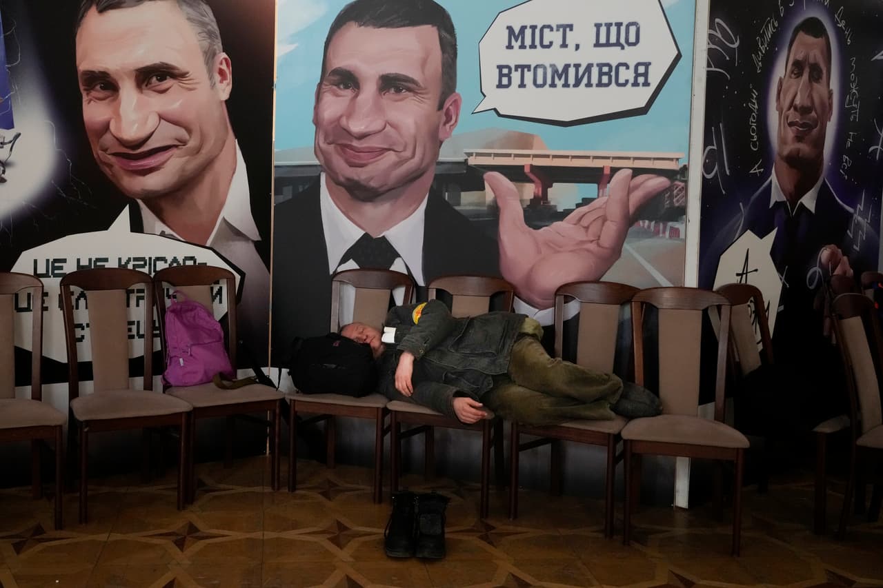 Un civil armado duerme frente a una pancarta con el rostro de Vitali Klitschko, alcalde de Kiev y excampeón de box en la categoría de peso pesado, quien también se ha unido a las fuerzas armadas de resistencia.