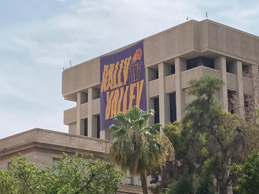 Una manta gigante cuelga en uno de los edificios de la legislatura con el logo de los Suns. Se lee Rally the Valley.