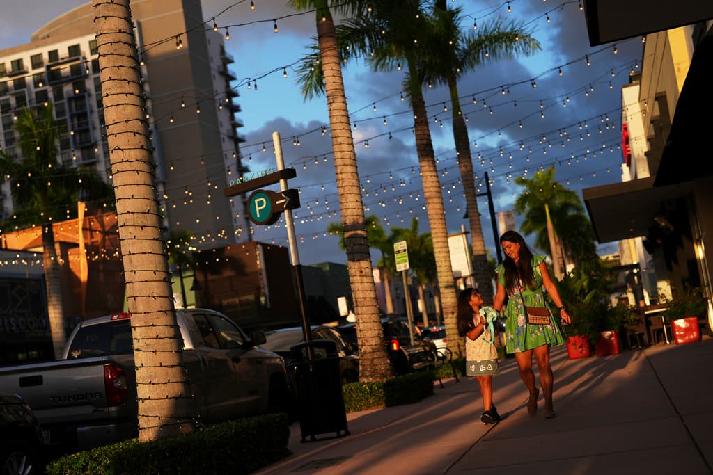 Una mujer y una niña caminan por una calle comercial, en Doral, Florida, el sábado 5 de abril de 2025. (AP Foto/Rebecca Blackwell)