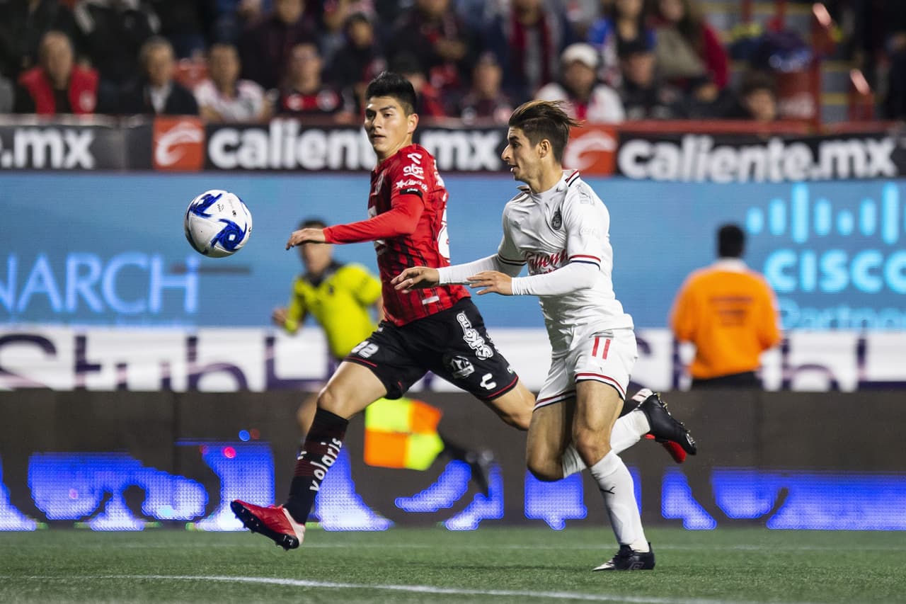 Isaac Brizuela alarga la pelota para ganar por velocidad, pero Vladimir Loroña hace correctamente su recorrido y ahoga la jugada del delantero de Chivas.