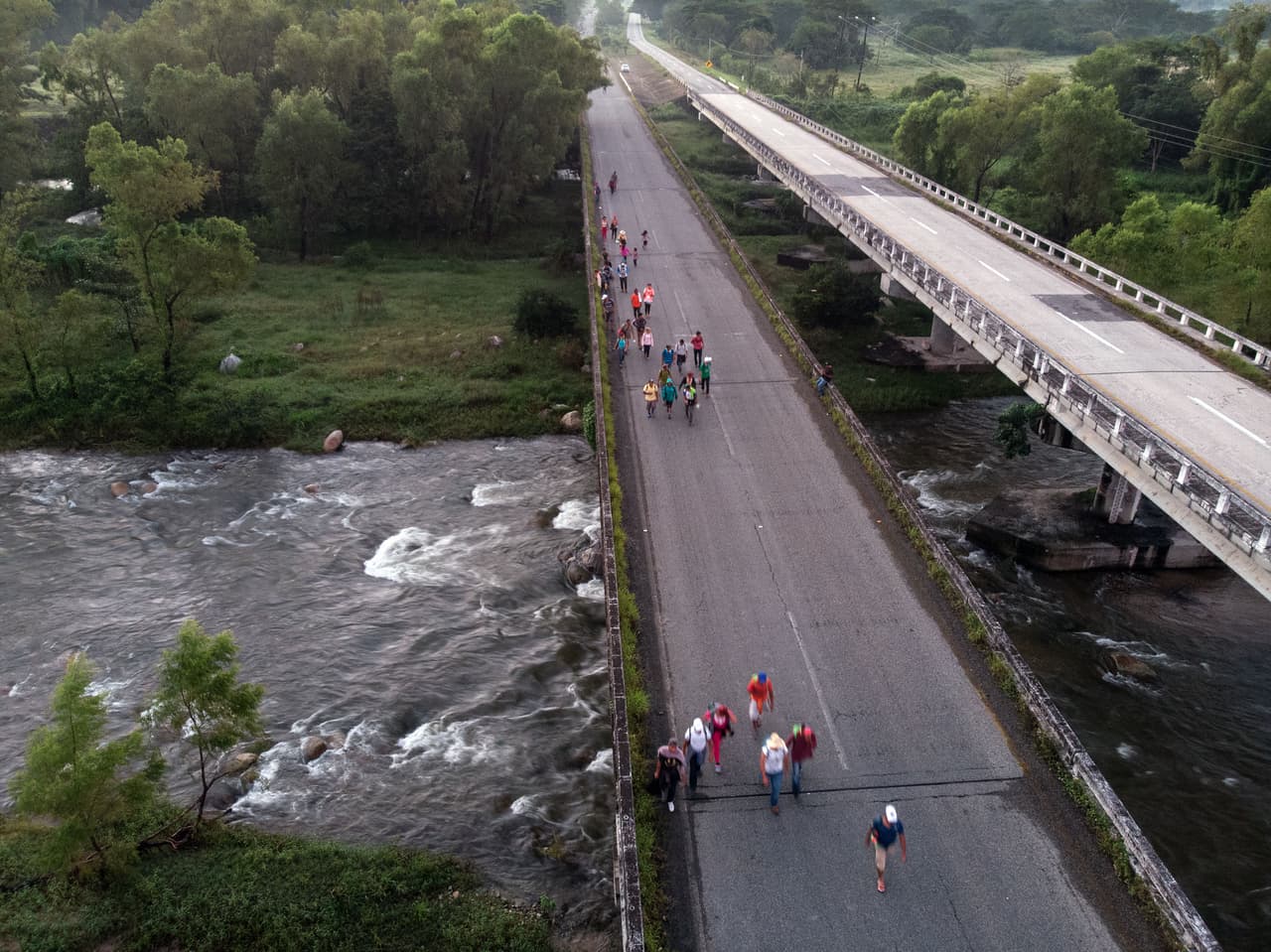 El grupo se ha dispersado en las diferentes etapas del viaje. En la fotografía unos cuantos viajantes cruzan un puente en Mapastepec, Chiapas.