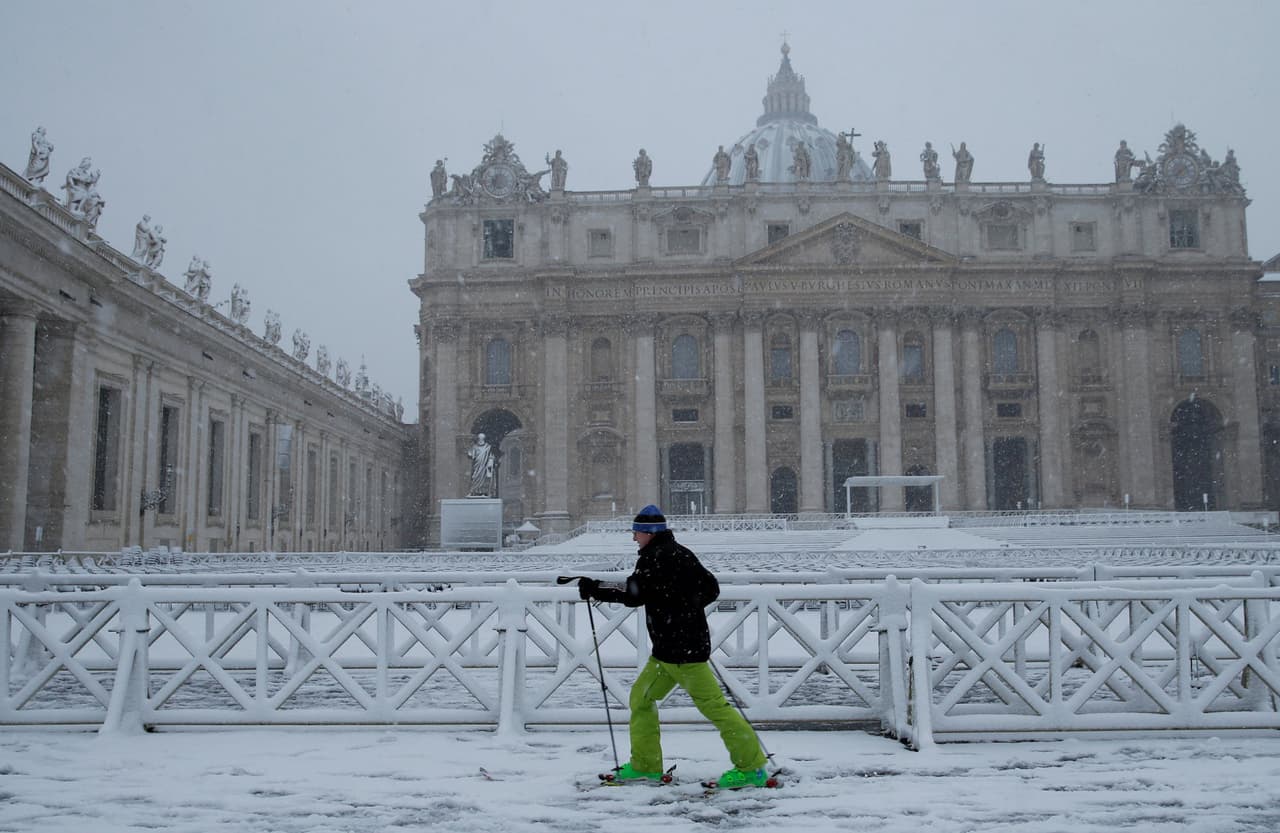 Otra vista de la plaza de San Pedro, en el Vaticano. Un hombre camina con los utensilios especiales para andar sobre la nieve.