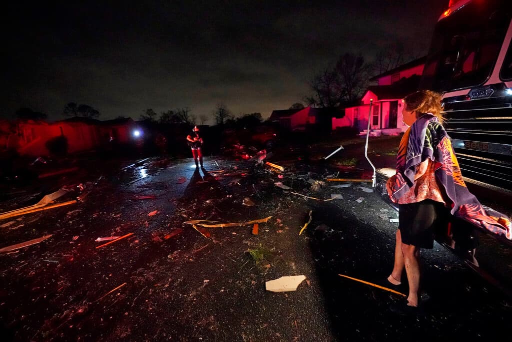 Melodie Maher observa desde el camión de los bomberos a su hijo Claude Maher, mientras los socorristas rescatan a su perro en su casa, que quedó severamente dañada por el tornado.