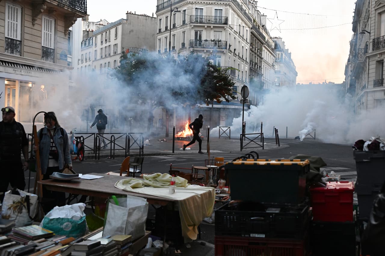 Un manifestante corre entre gases lacrimógenos mientras se celebra un mercadillo durante los enfrentamientos entre manifestantes y agentes de policía en París, el domingo 18 de octubre de 2026.