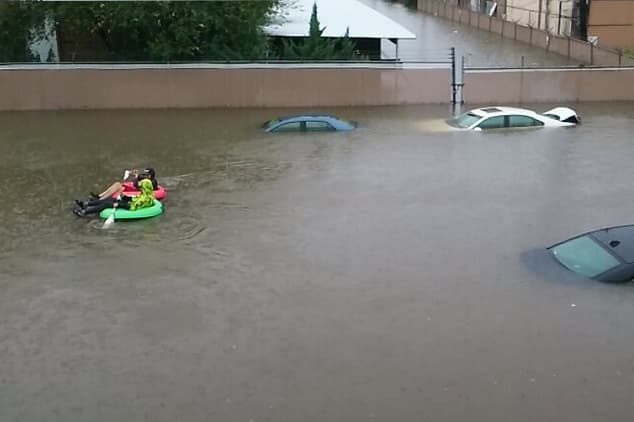 Residentes de un complejo de apartamentos que sufrió severas inundaciones tratan de evacuar en un flotador.