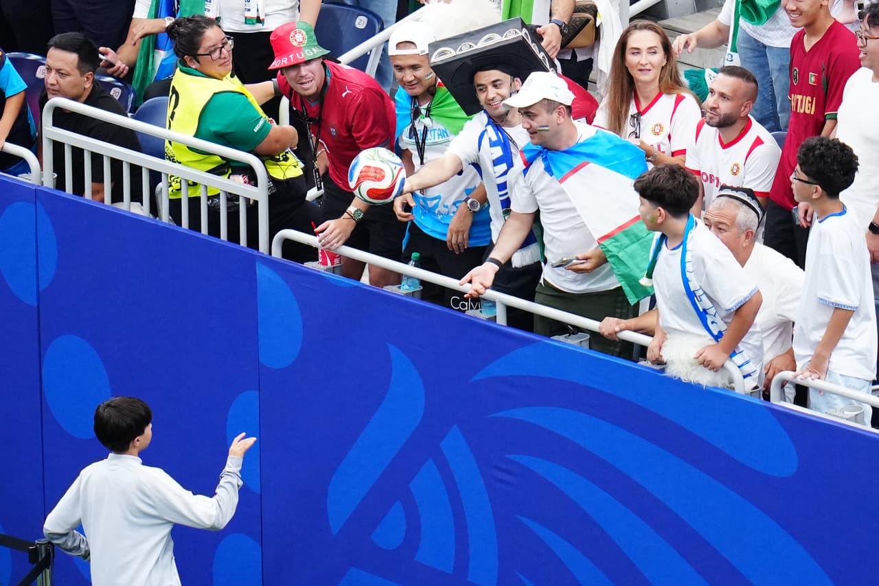 Los aficionados devuelven un balón que acabó en las gradas durante el partido de fútbol del Grupo K de la Copa Mundial entre Portugal y Uzbekistán en Houston.