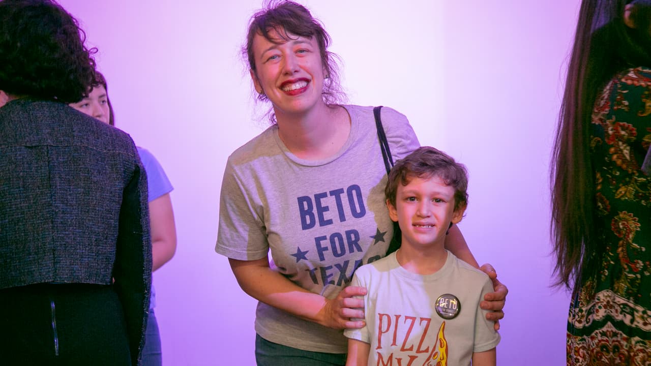 Madre e hijo esperan en la fila para fotografiarse con el candidato al que visiblemente apoyan.