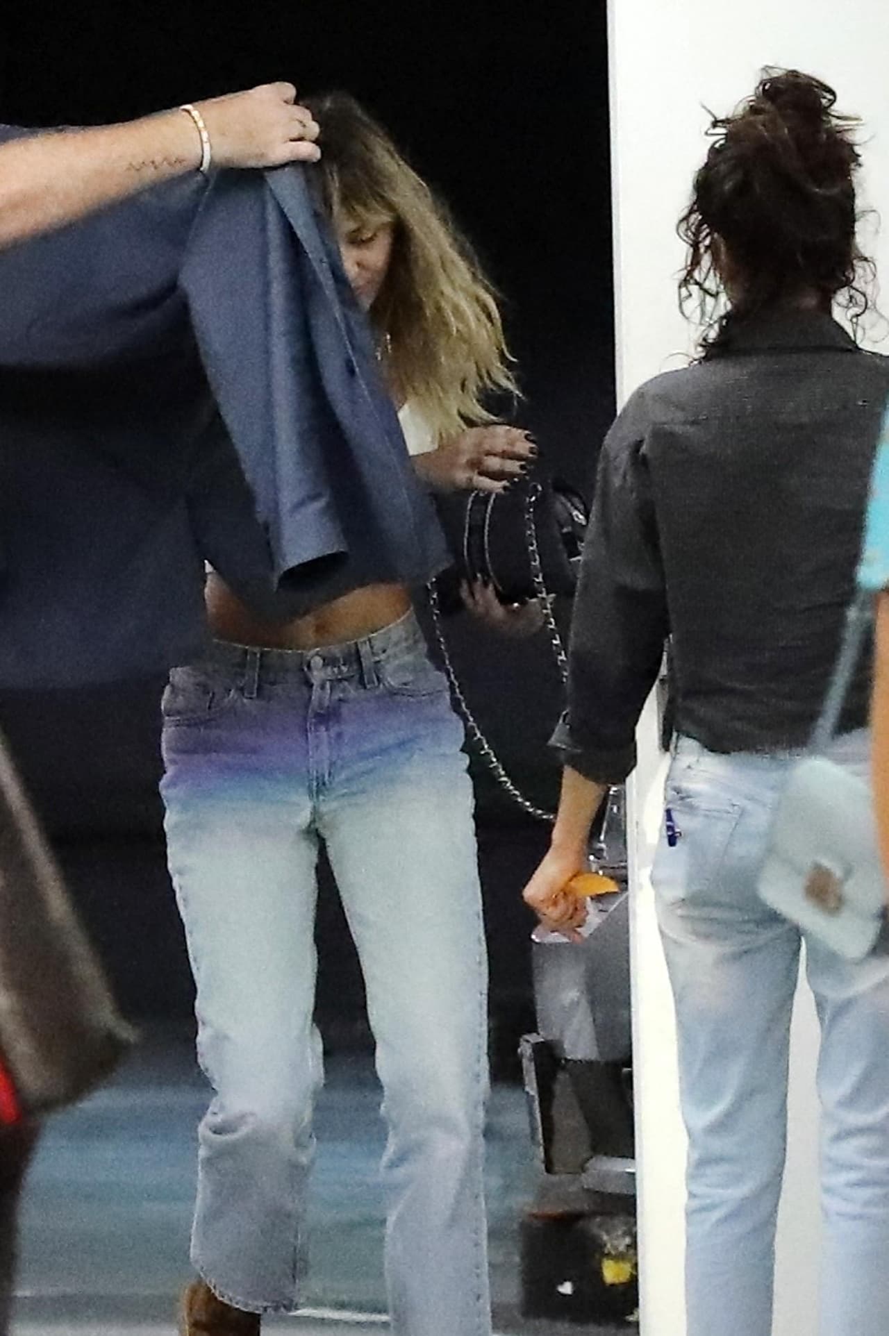 Cuando Miley Cyrus bajó de la camioneta de su mamá, alguien le colocó una chaqueta para intentar proteger su identidad.