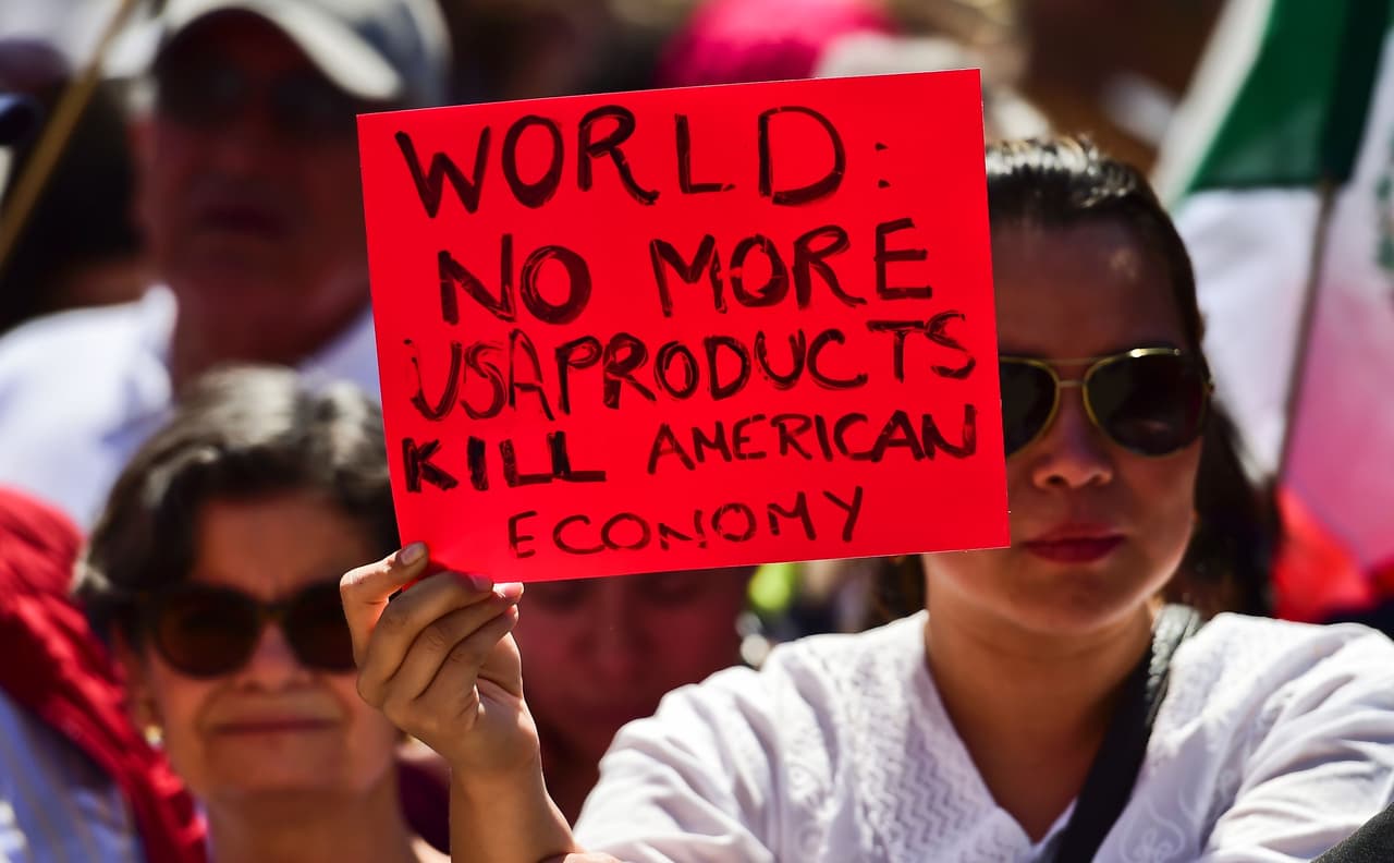 Una mujer marcha con una pancarta que dice: "Mundo: no más productos estadounidenses. Matemos la economía americana".
