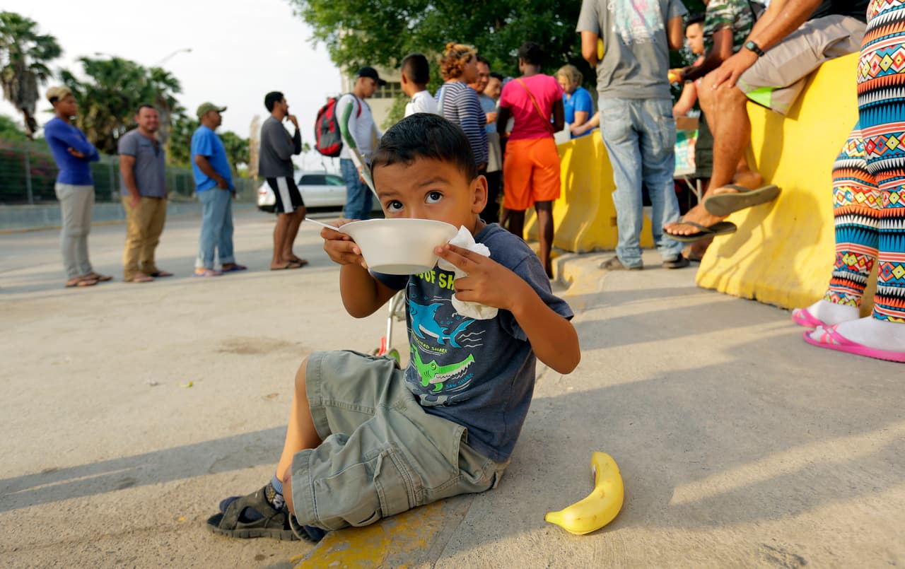 <b>Matamoros, Tamaulipas. Alrededor de 800 personas en la lista para solicitar asilo. </b>Al pie del puente que esta ciudad con Brownsville, Texas, se han pegado más de 20 hojas de papel en un tablero grande con los nombres escritos a máquina de los solicitantes. Los migrantes revisan el tablero diariamente para ver qué nombres han sido tachados con un marcador negro. En la fotografía William Linares, de 5 años, mientras comía de lo ofrecido por voluntarios en Matamoros. Viajó con su madre Suanny Gómez desde Honduras. Gómez dijo a la agencia AP que no tenía para pagar una tarifa por la solicitud de asilo, 
<a href="https://www.univision.com/noticias/politica/trump-quiere-cobrar-a-quienes-soliciten-asilo-y-dar-seis-meses-para-que-se-decidan-sus-casos">una de las propuestas del presidente Donald Trump. </a>