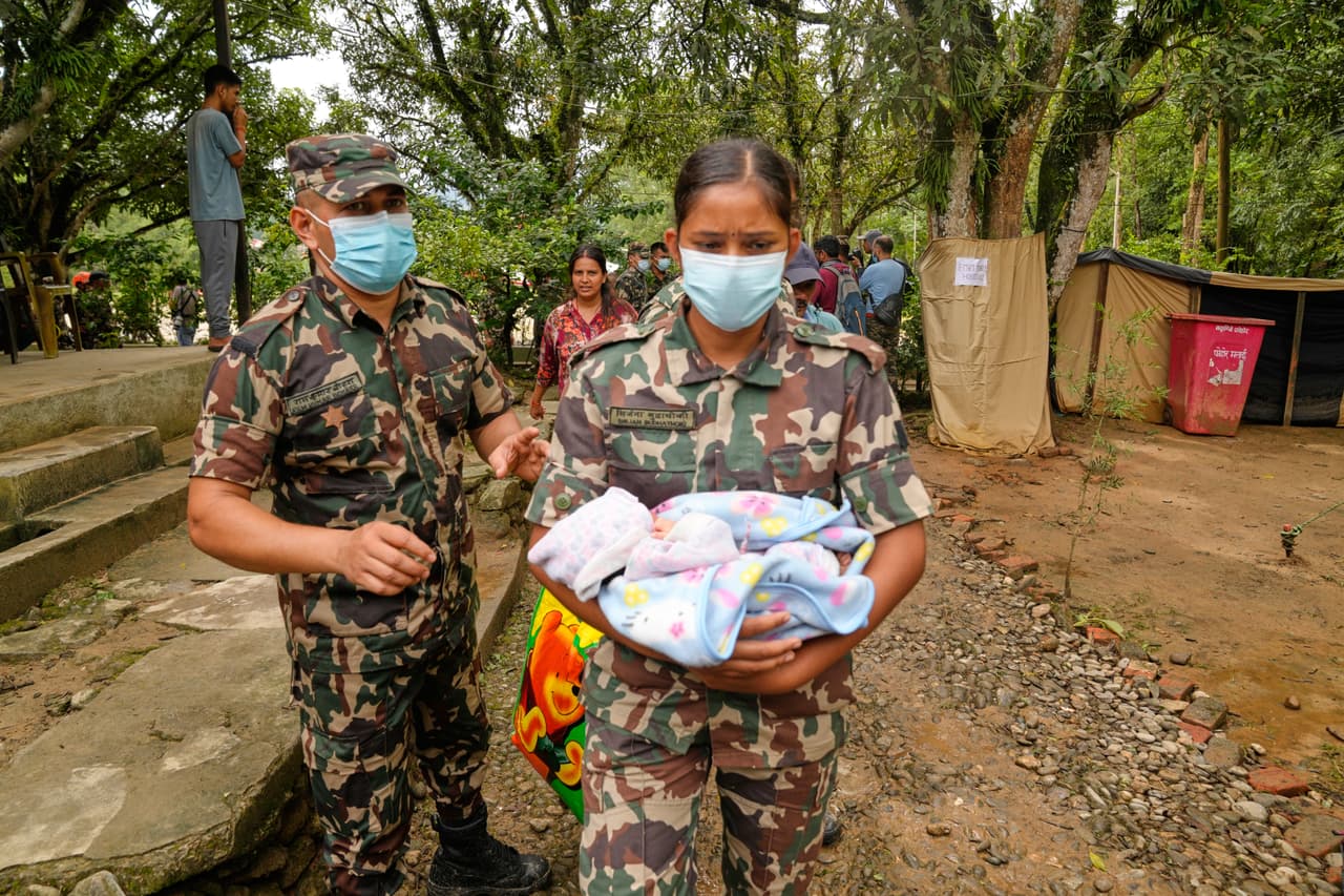 Un soldado del ejército nepalí lleva a un bebé recién nacido para su madre después de que fueran rescatados de una zona aislada por inundaciones repentinas y para su registro en el distrito de Nuwakot, Nepal, el sábado 29 de agosto de 2026.